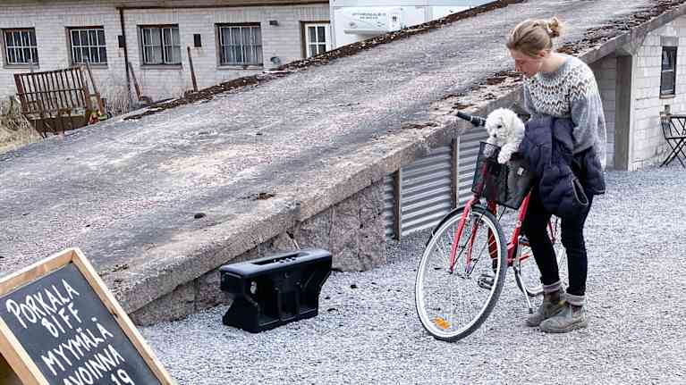 en kvinna med sin cykel och hund ute på ett lantbruk 