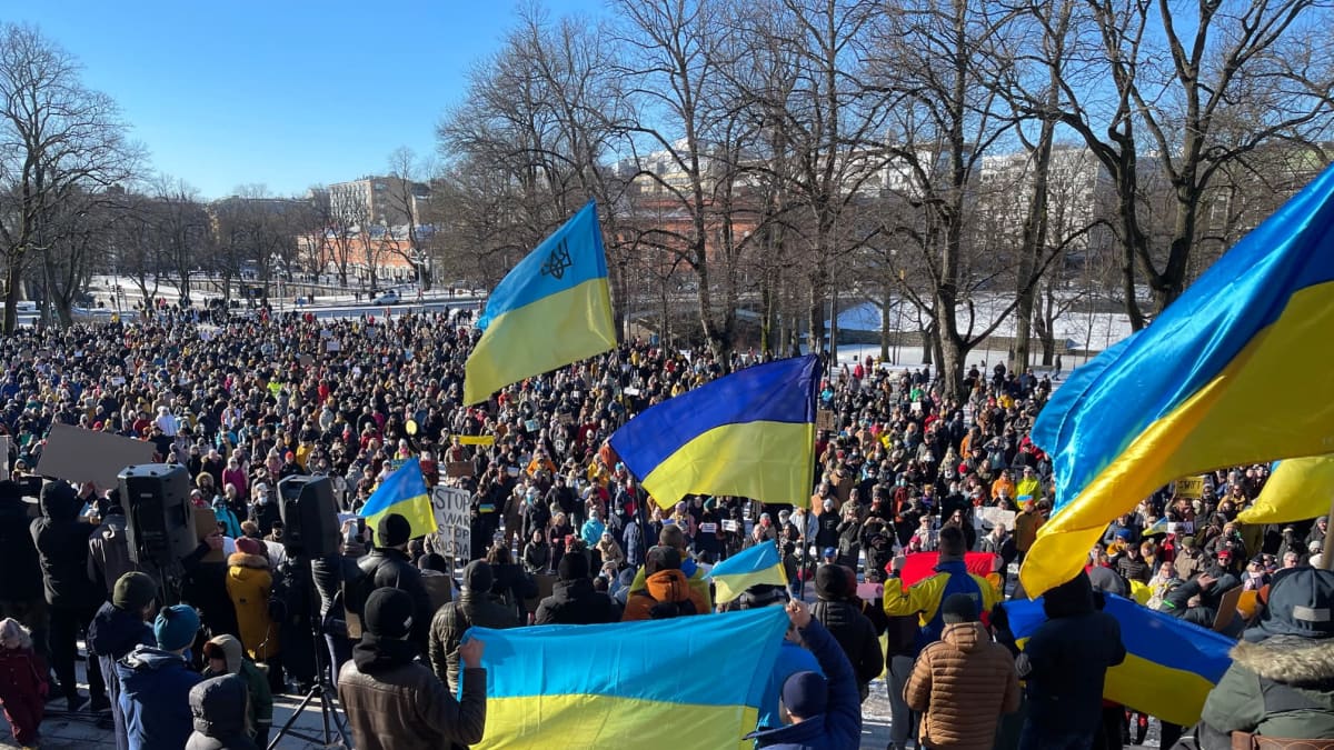 Mielenosoittajia, iso joukko ihmisiä Turussa ulkona. Ukrainan lippuja.
