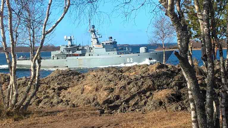 Ett militärfartyg som kör väldigt nära land på Åland.