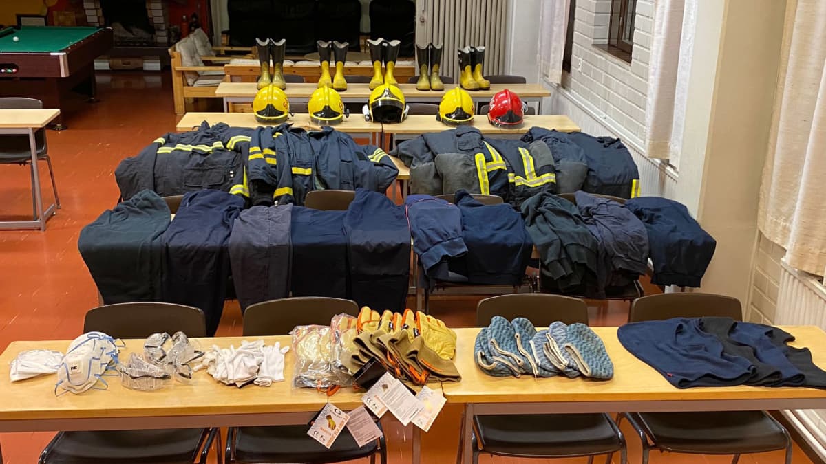 Erilaisia pelastushenkilöstön tarvikkeita ja vaatteita aseteltuna riveihin pöydälle.