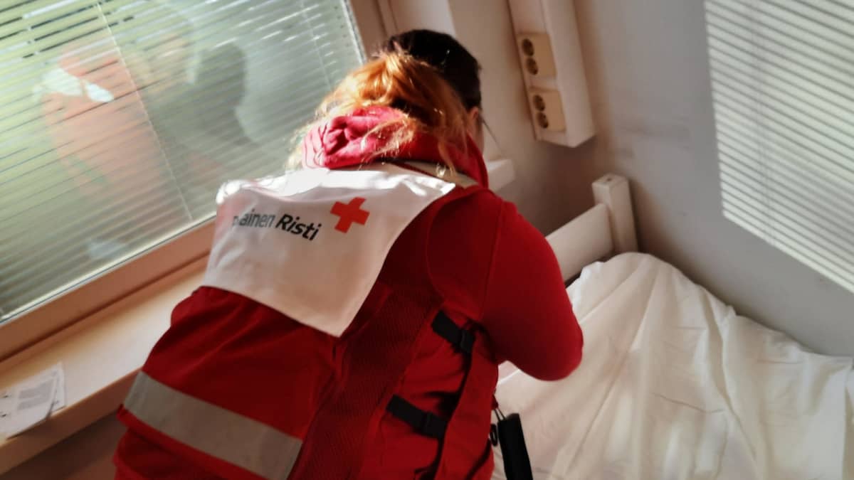 SPR:n tunnuksin varustettu henkilö petaa sänkyä Kaupin vanhassa sairaalassa. 