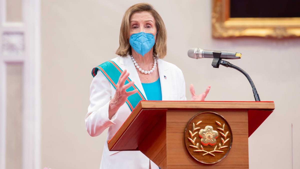Nancy Pelosi i munskydd vid ett talarpodium.