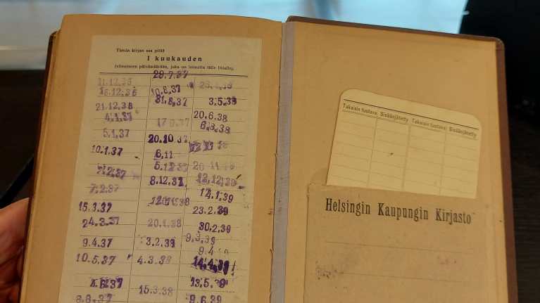 Vanha kirja, jossa on taskussa lainauskortti ja leimoja lainausvuosilta 1936–1939.