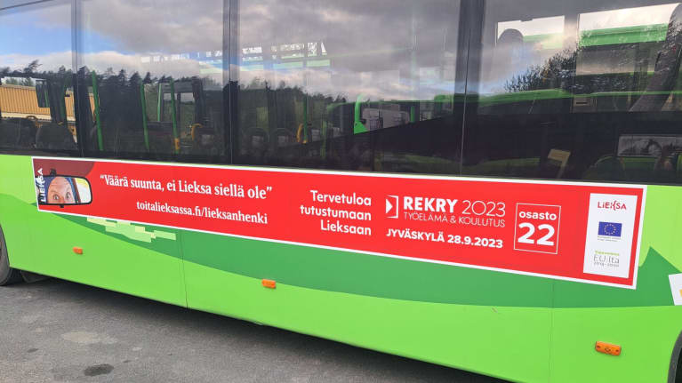 Mainos vihreän linja-auton kyljessä.