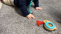 A baby crawling on the floor with a toy.