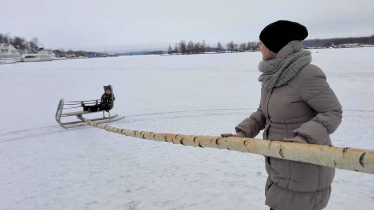 Nainen työntää napakelkan aisaa, napakelkan kyydissä lapsi.