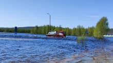 Hinausauto kuljettaa lavallaan henkilöautoa tulvaveden keskellä