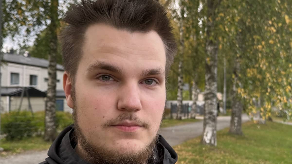 Mies katsoo kameraan. Taustalla on koivuja.