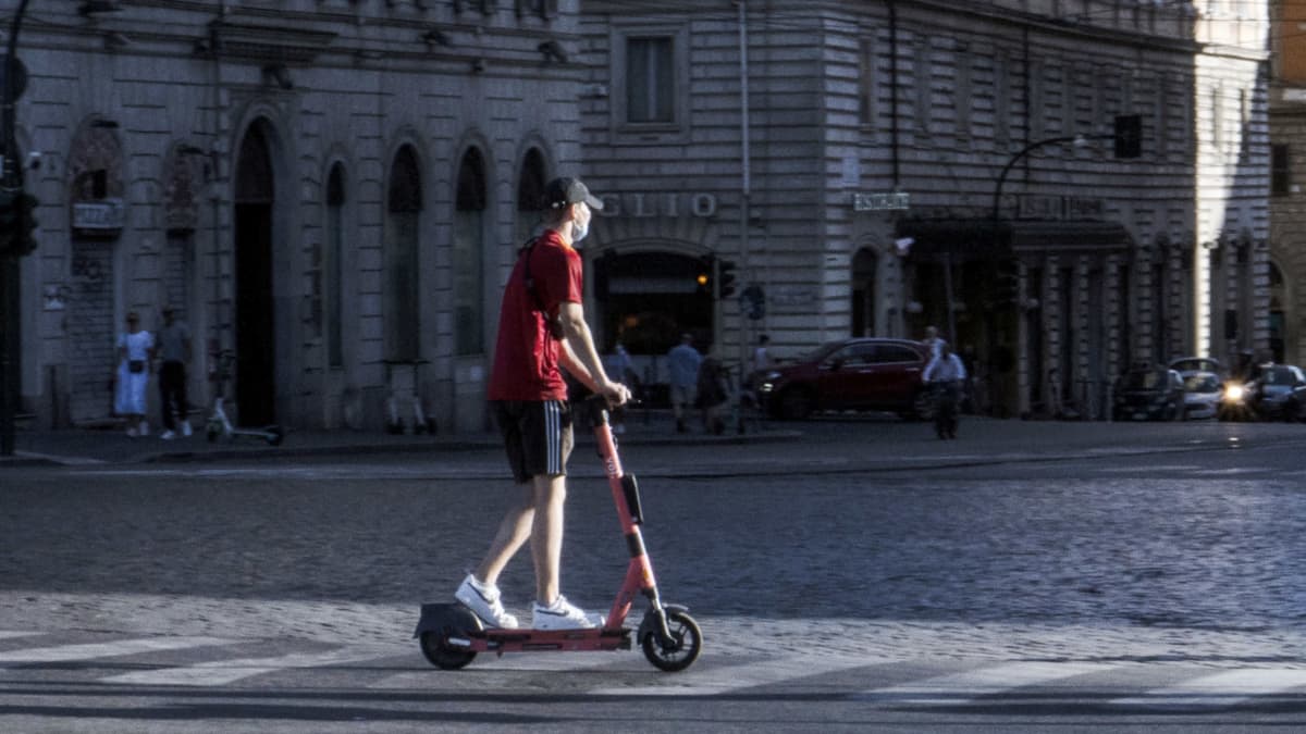 Henkilö sähköpotkulaudalla Rooman kadulla.