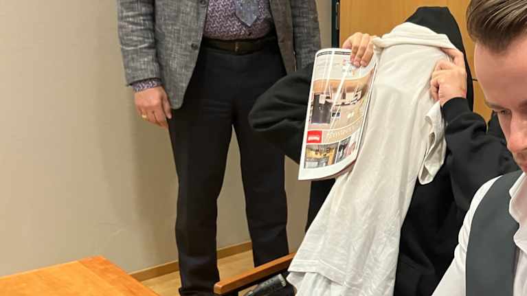 The suspect in court covered his face with a white T-shirt.