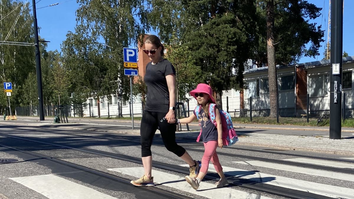 Äiti saattaa lasta kadun yli.
