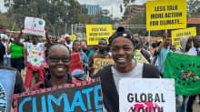 Nuori nainen ja mies kylttien kanssa ilmastomielenosoituksessa Nairobissa Keniassa