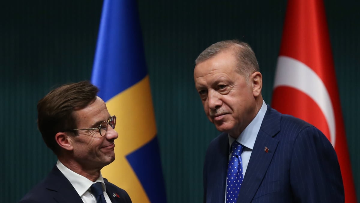 Kaksi miestä Ruotsin ja Turkin lippujen edustalla. 