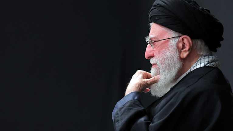 Iranin johtaja Ali Kahmenei istuu sivuttaiskuvassa hieroen partaansa.