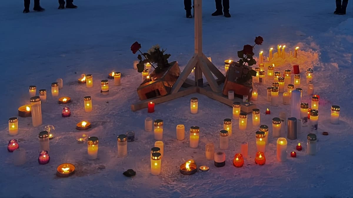 Kynttilöitä ja ruusuja Ukrainan lipun alle tuotuna.