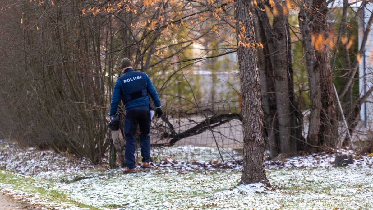 Poliisi tutkii maastoa hieman lumisessa maisemassa.