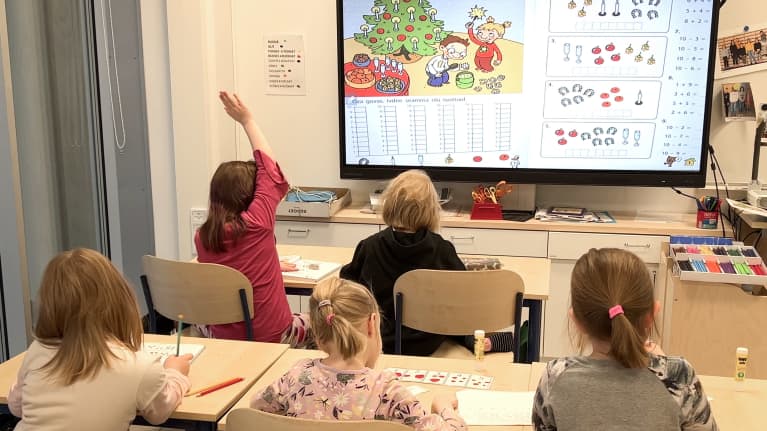 Viisi alakouluikäistä oppilasta opiskelee saamen kieltä koululuokassa ison näytön äärellä.