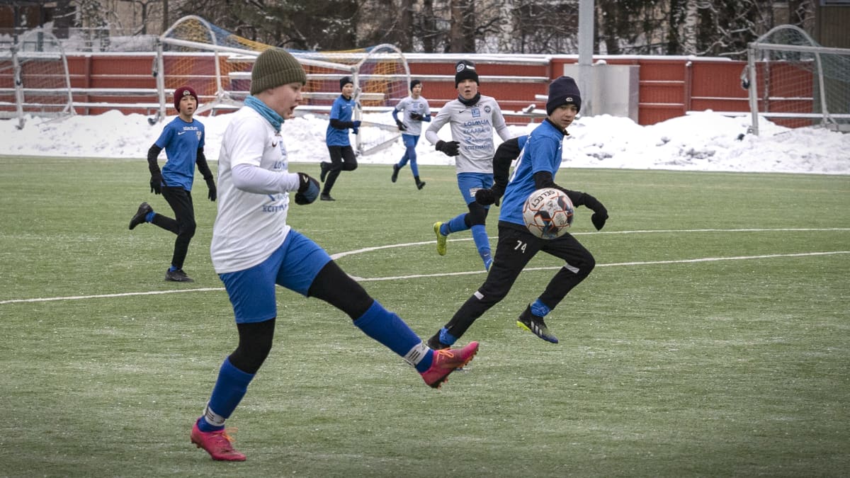Lapset pelaavat jalkapalloa Oulunkylän urheilupuiston kentällä