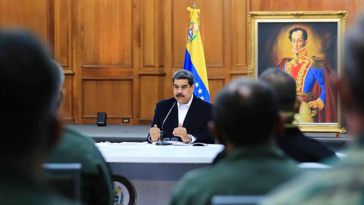 presidentti Maduro pöytänsä ääressä, edessä miesten hahmoja