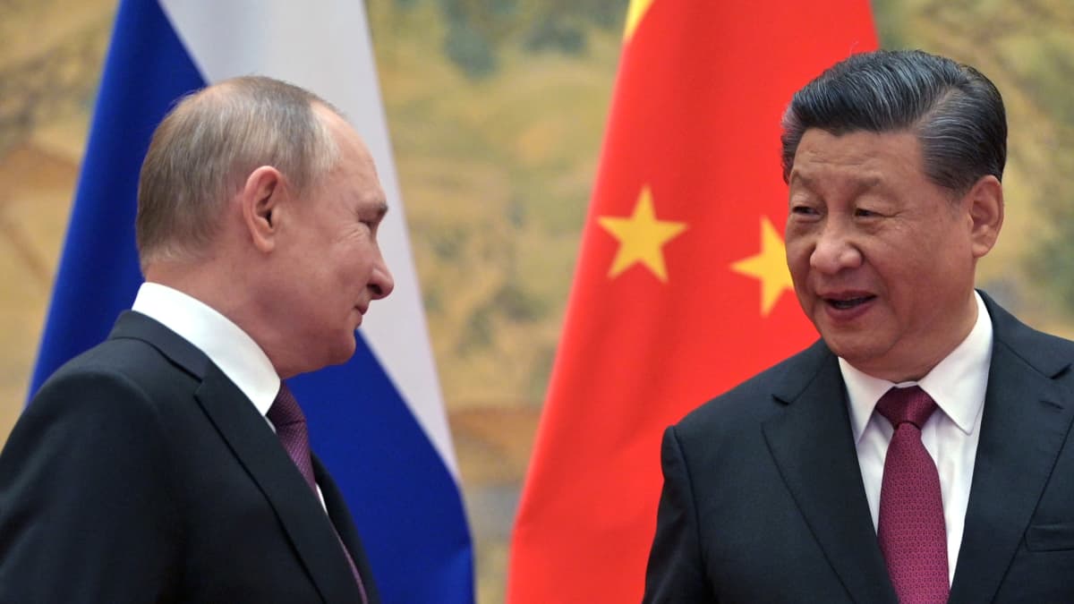 Venäjän Putin ja Kiinan Xi keskustelevat, maiden liput taustalla. 