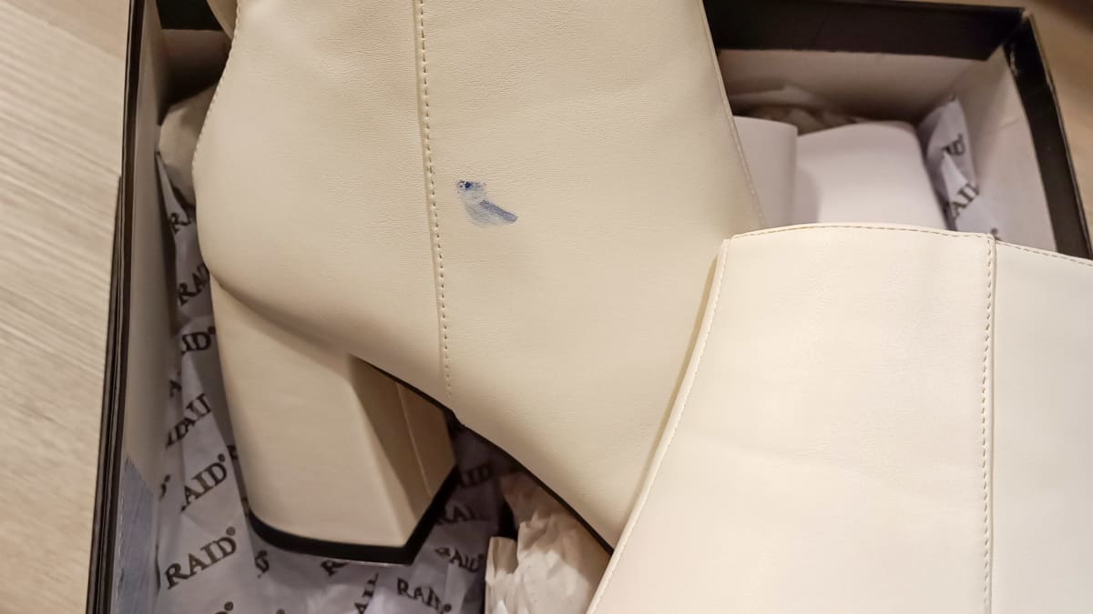 Valkoiset korkokengät, joissa on sininen likatahra sivussa. 