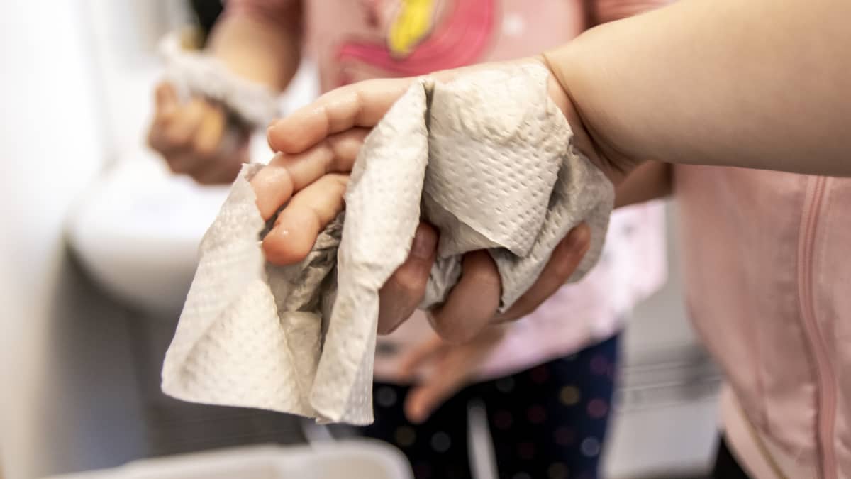 Tytöt kuivaavat käsiään paperipyhkeeseen.