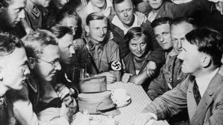 Adof Hitler ihailijoiden ympäröimänä kesken aterian.