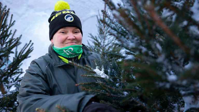 Joulukuusikauppias torilla kuusien ympäröimänä.