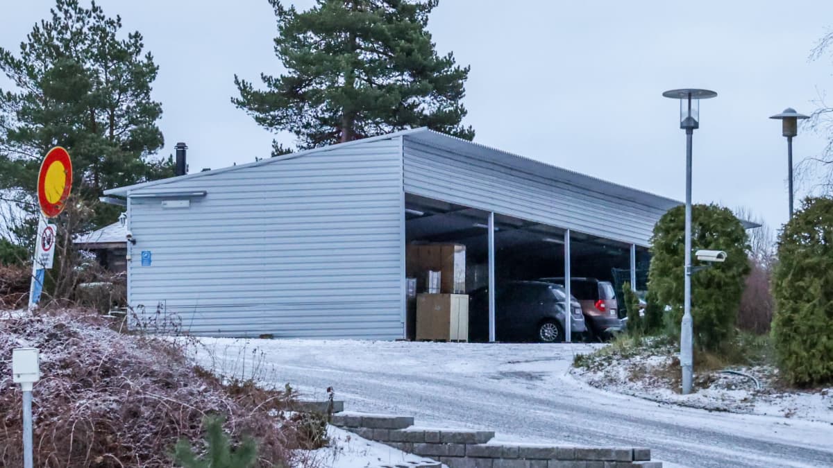 Harmaa autokatos jonka alta pilkistää pahvilla päällystettyjä kuormalavoja.