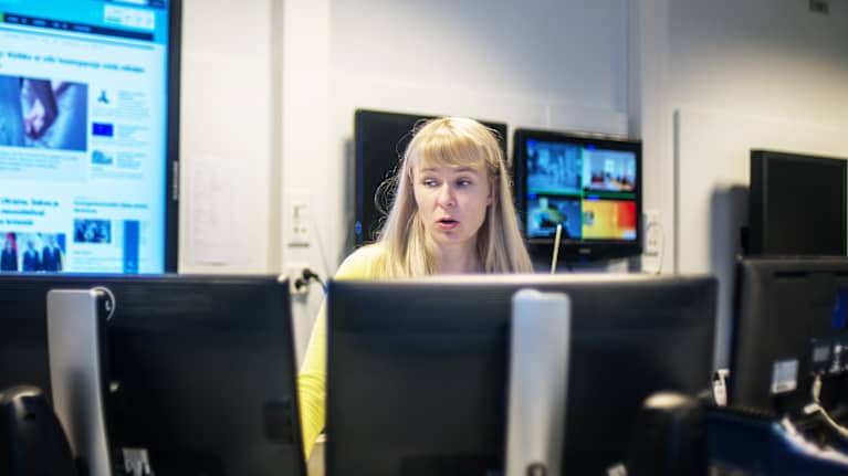 toimittaja katselee kuvia useilta rinnakkaisilta monitoreilta. Taustalla näkyy isoja ruutuja, joissa on kuvia verkkouutisista ja uutislähetyksistä