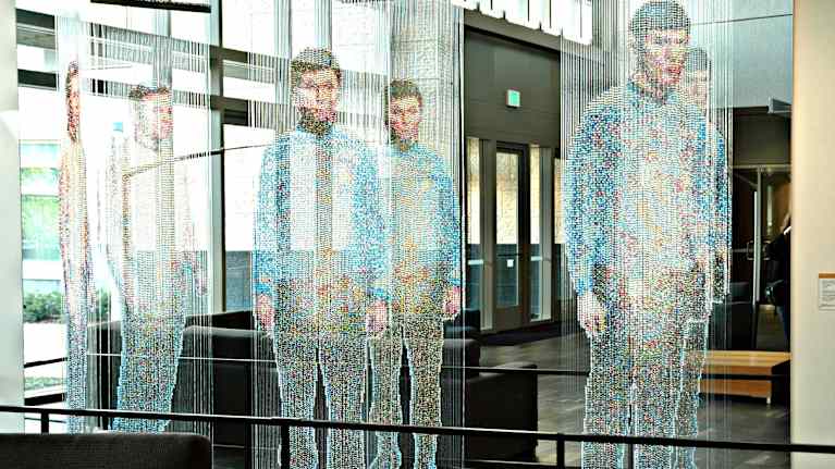 En konstinstallation med flera avbildningar av en man i blå skjorta och mörka byxor, skapad med olika tekniker för att ge en illusion av transparens.