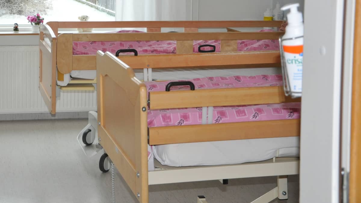 Kaksi sairaalasänkyä, joissa on vaaleanpunaiset päiväpeitteet.