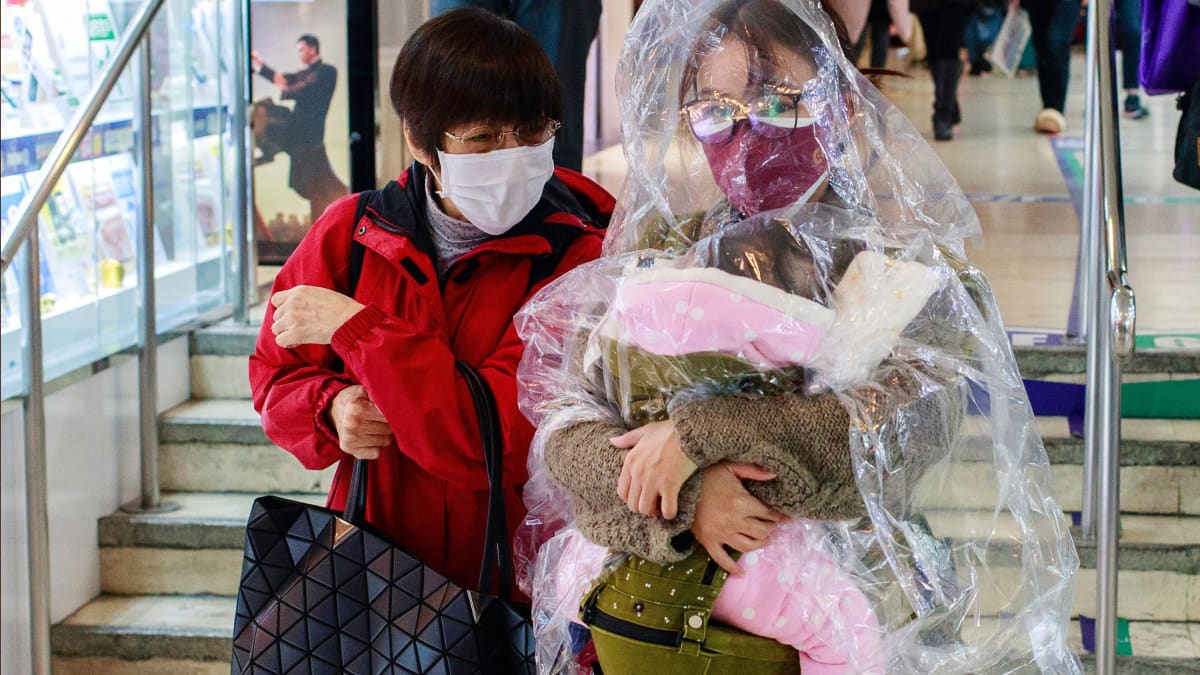 Nainen on suojannut itsensä ja lapsensa läpinäkyvällä sadeviitalla Hongkongissa.