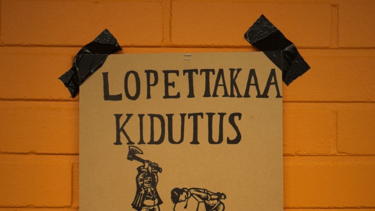 Kyltti, jossa lukee "Lopettakaa kidutus leikkaisitte kunnolla". Pyöveli katkaisee päätä.