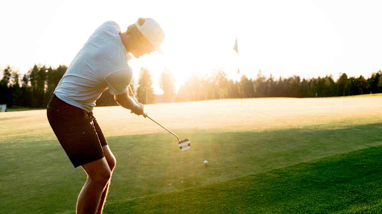 Golfari greenillä hienossa vastavalossa.