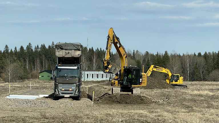 Kaivinkoneet tasoittavat maata ja kuorma-auto on valmiina kuljettamaan maa-ainesta.