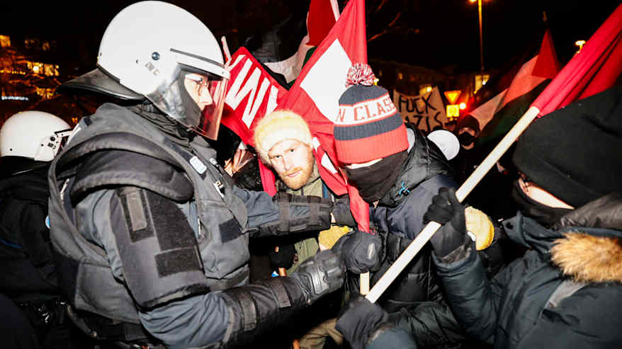 Mielenosoittajat ja poliisit kohtaavat. Mielenosoittajat heiluttavat esimerkiksi Palestiinan lippuja. 