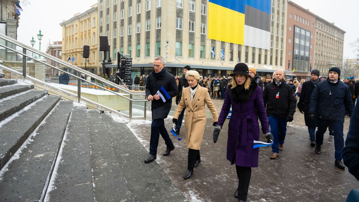 Kaksi naista ja mies talvivaatteissa kävelevät Viron pienoisliput käsissä.