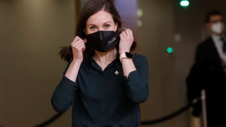 Sanna Marin laittamassa kasvomaskia kasvoilleen.