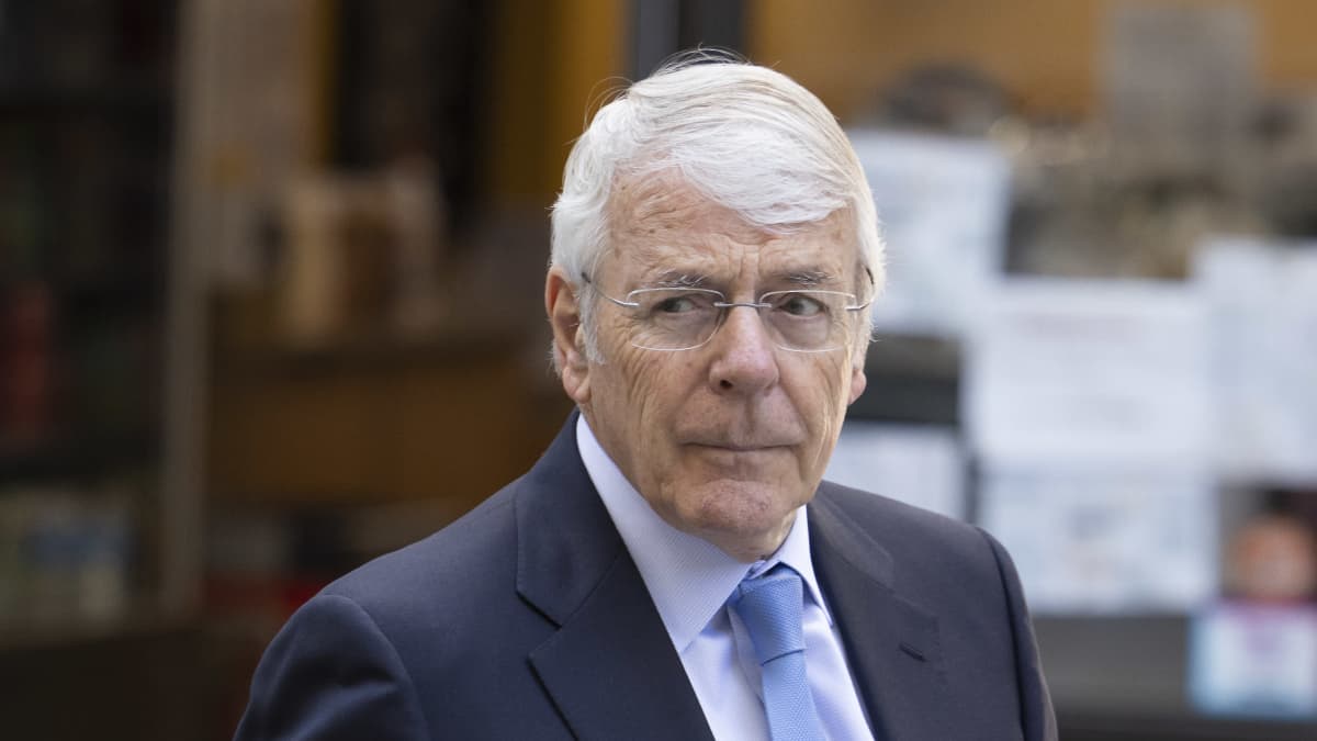 En gråhårig man i blå kostym i närbild. Mannen är John Major.