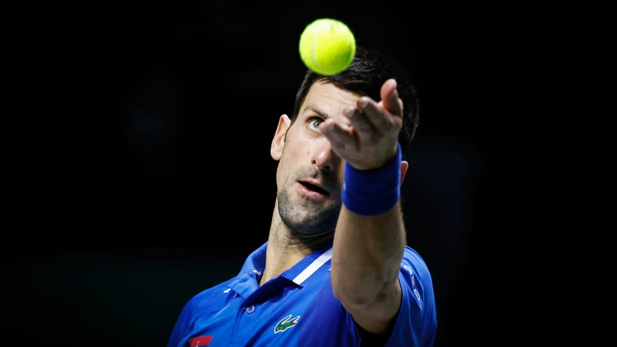 Novak Djokovic kastar upp en tennisboll i luften.