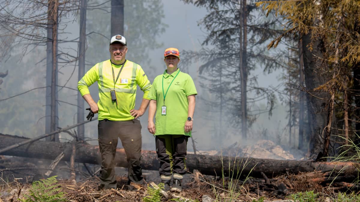 Kulotetun savuavan alueen keskellä seisovat Metsäkeskuksen Johanna Virtanen ja yrittäjä ET Kärkkäinen