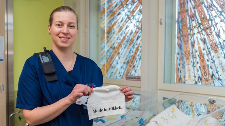 Anne Pikkarainen esittelee vauvan pipoa jossa lukee: Made in Mikkeli.