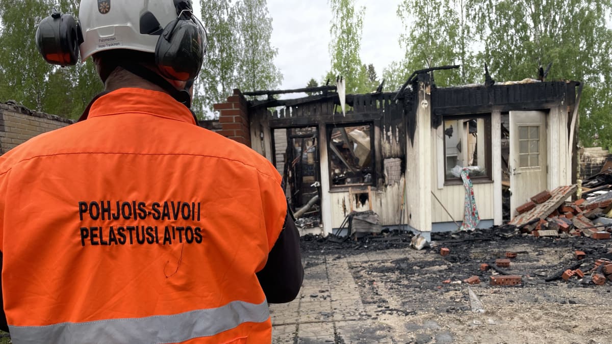 Pohjois-Savon pelastuslaitoksen palotutkija palaneen rivitalohuoneiston edessä. 