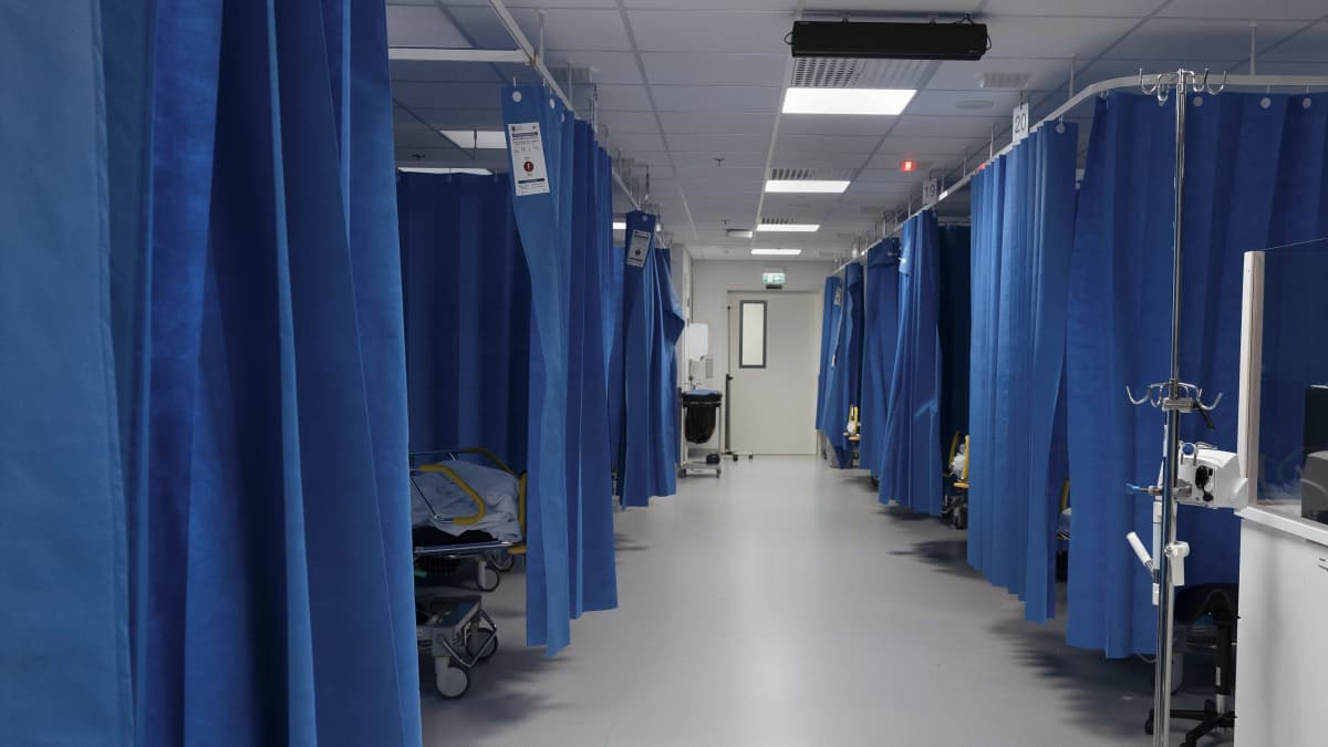 Keski-Suomen keskussairaala Novan päivystyksessä huone, jossa on verhoilla rajattuja potilaspaikkoja. Paikkoja on käytävän kahdella puolella. 