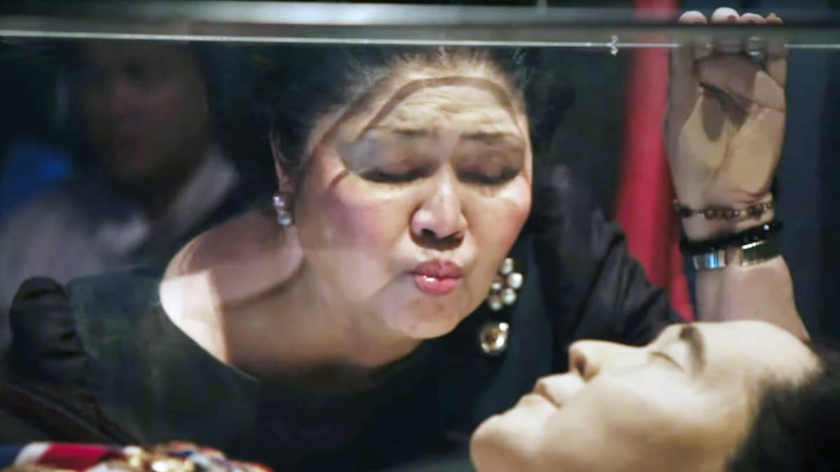 Imelda Marcos suutelee miehensä lasiarkun pintaa. Lasin alla on Ferdinand Marcosin ruumis.