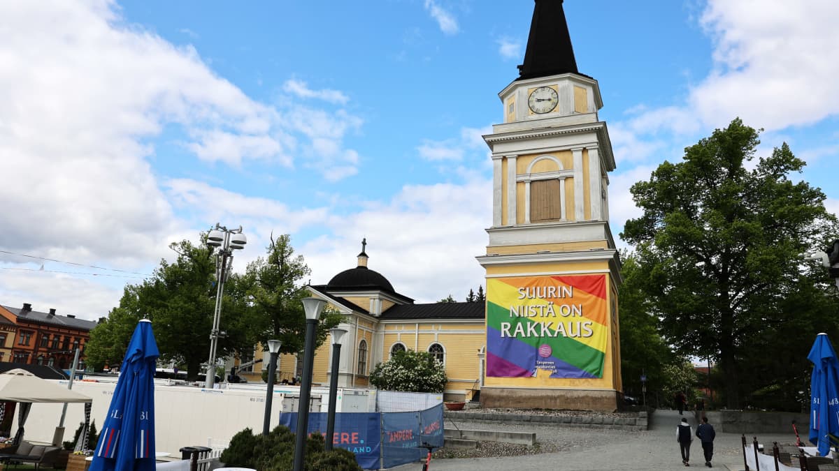 Sateenkaarilippu Tampereen Vanhan kirkon kellotornin seinässä. Lipussa teksti: Suurin niistä on rakkaus.