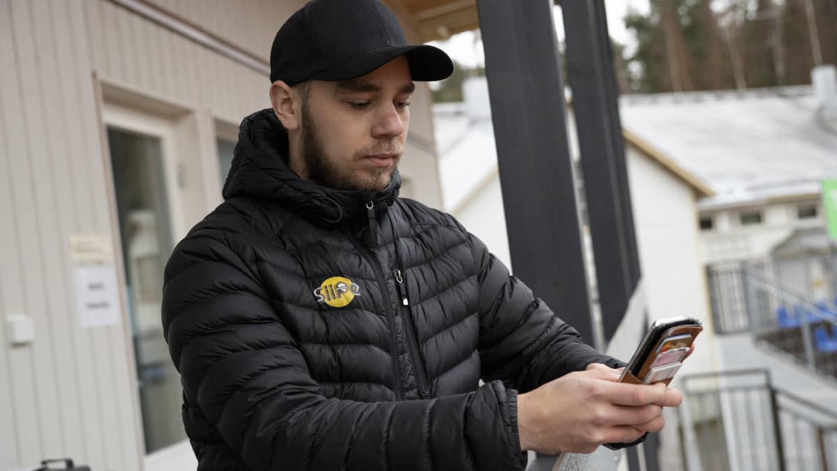 SiiPen pelaaja Eemeli Paldanius selaa kännykkää pesäpallostadionilla Siilinjärven Mantulla.