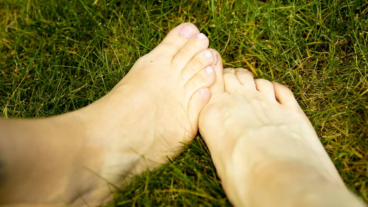 Kaksi jalkaa ristissä nurmikolla.