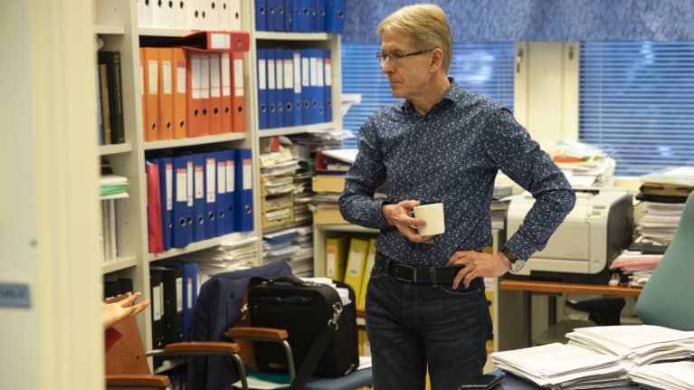 Seppo Ylä-Herttuala seisoo työhuoneessaan kahvikuppi kädessä